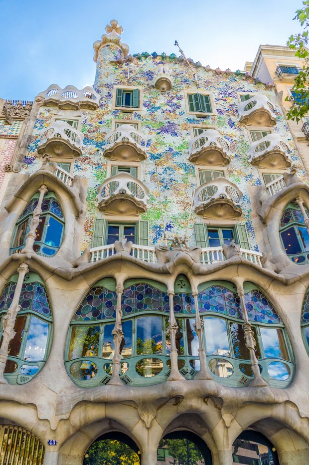 Casa Batlló's façade: mosaic tiles in blues and greens, mask-shaped balconies and bone-like columns around stained-glass windows.