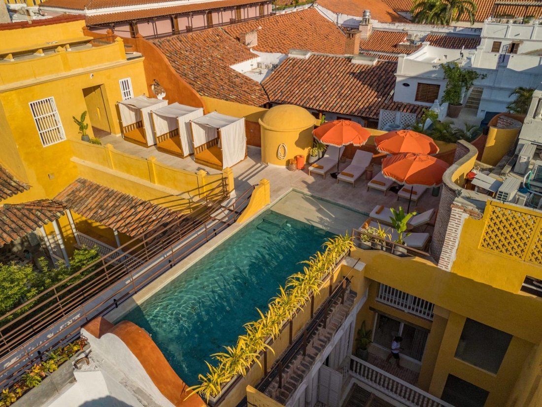 Looking down on the hotel roof: a long turquoise pool, curtained cabanas and orange parasols, set among the ochre walls and terracotta rooftops of the old city.
