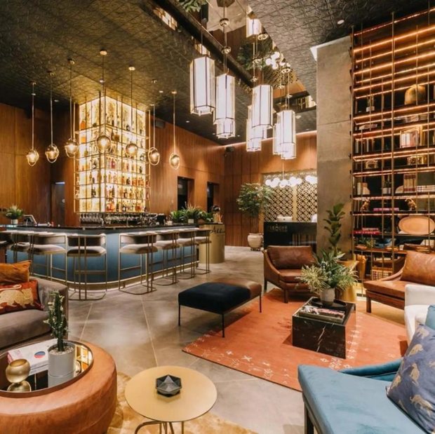 The lobby bar: a lit back-bar wall of bottles, brass pendant lanterns, walnut panelling and low leather seating.