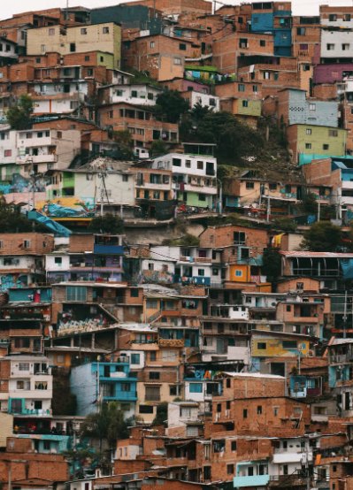 Comuna 13: brightly painted brick houses stacked tightly up a steep hillside, balconies and washing lines layered one above the next.